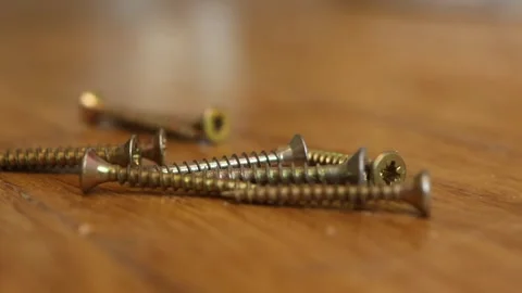 Iron wood screw rolling on table towards a pile of screws Stock Footage 325833874