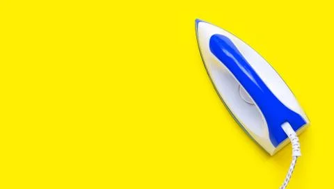 Iron on yellow background. Stock Photos