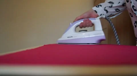 Ironing and steaming shocking pink fabric using a white iron, caucasian woman Stock Footage 43666433