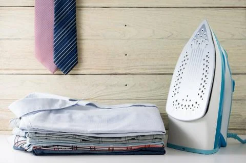 Ironing clothes laundry housework with stack of shirts and tie hanging Stock Photos