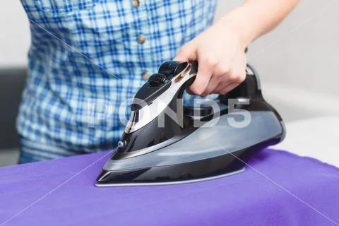 Ironing purple linen iron on Ironing Board Stock Photos