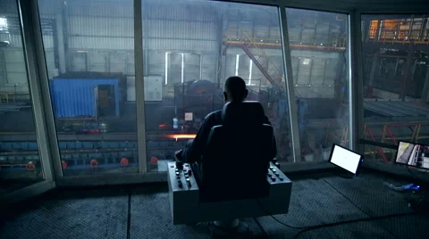 Ironworks plant. Worker controls moving of burning hot billet Stock Footage 68294622