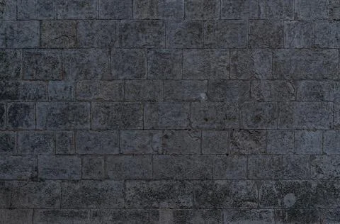 Irregular dark gray bricks dirty and wet wall background Stock Photos