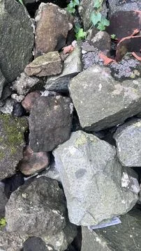 Irregular gray and brown rocks stacked together with patches of moss and gree Stock Photos