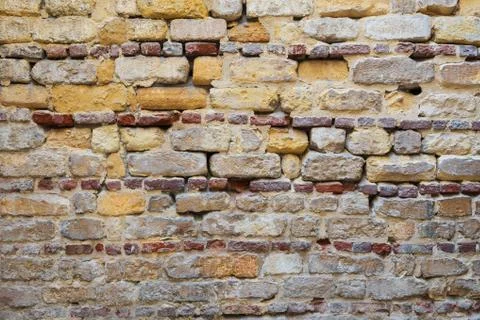 Irregular pattern of yellowish, red and gray grunge weathered uneven bricks Stock Photos