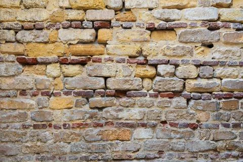 Irregular pattern of yellowish, red and gray grunge weathered uneven brick... Foto stock