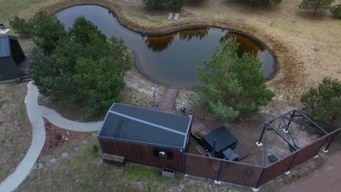 Irregular pond, dock, lounge chairs, and wood cabin with logo Stock Footage 337264765