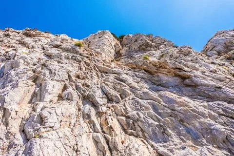 Irregular rock face with blue sky in the background on a beautiful warm sunny Stock-Fotos