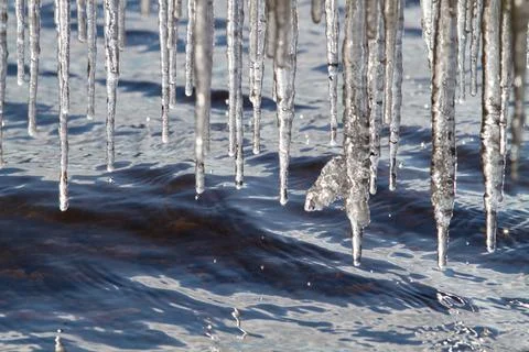 An irregular row of icicles hangs above the water Stock Photos