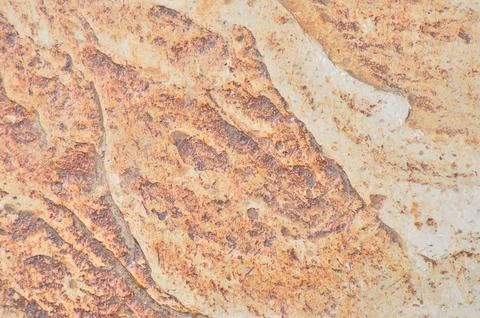 Irregular surface texture of chipped stone with orange tones Stock Photos