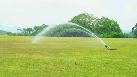The Irrigation Sprinkler System is in full action on a vibrant green field Stock Footage 308393982