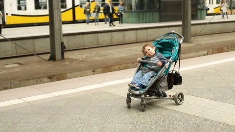 Irritated boy sitting on the stroller in the platform Stock Footage 76039669