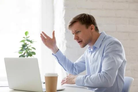 Irritated businessman having problems with computer gesticulating feels angry 库存照片