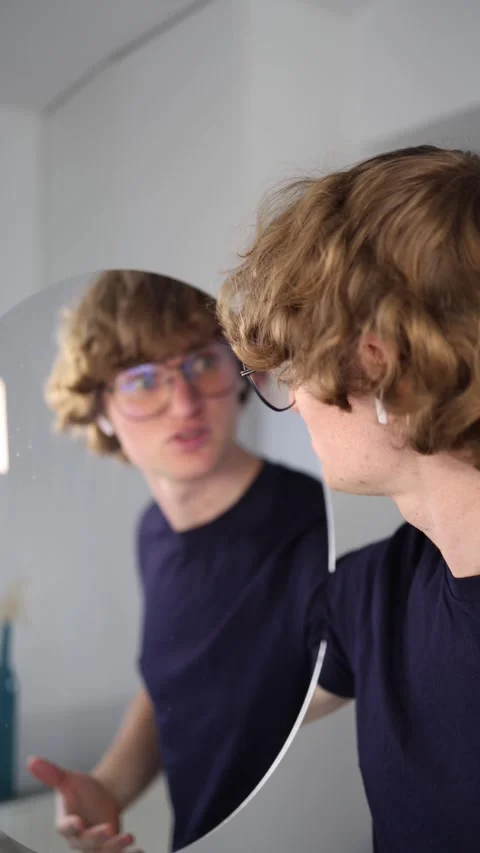Irritated expression as a young man talks to his reflection with exaggerated ges Stock Footage 313269019