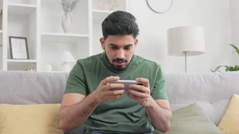 Irritated guy playing games on smartphoen and losing Stock Footage 256078245