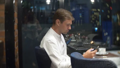 Irritated man checking a cell phone at night in a restaurant. 4k, background Stock-Footage 86439991