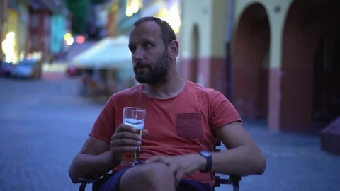 Irritated man drinking beer in the old town and waiting for someone  Stock Footage 103517956