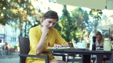 Irritated woman checking time while writing something in her notebook Stock Footage