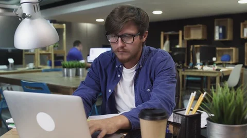 Irritated young man with glasses working on laptop in office Stock Footage 121775367