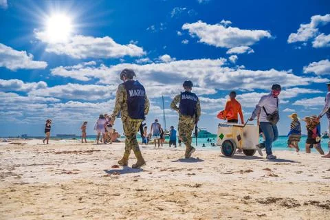 ISLA MUJERES ISLAND, MEXICO - APR 2022: Militaries walking along the beach wi Stock Photos