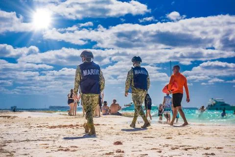 ISLA MUJERES ISLAND, MEXICO - APR 2022: Militaries walking along the beach wi Stock Photos