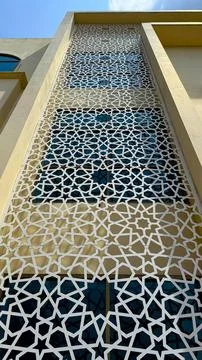 Islamic geometry pattern screen adorning a tan building facade creates a capt Stock Photos