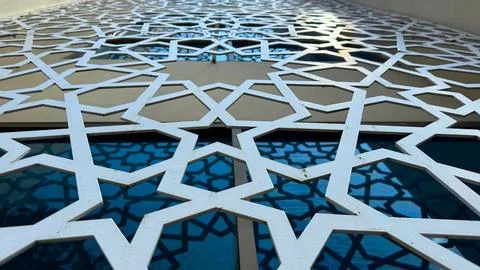 Islamic star pattern forms a geometric latticework against a blue window, cre Stock Photos