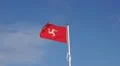 Isle of man flag, red manx flag with three legged man, blue sky, isolated HD Footage