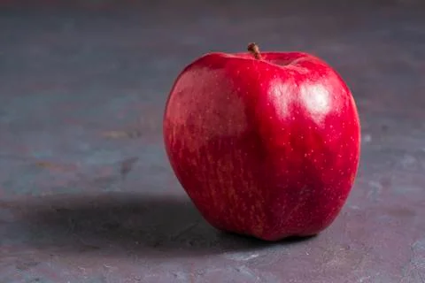 An isolate apple on a gray table. Delicious and healthy fruit. Stock Photos