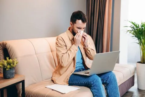 Isolate yourself if you are sick. Young professional man in casual clothes blows Stock Photos