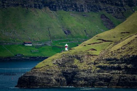 Isolated autonomous small lighthouse in Faroe Islands coast Stock Photos