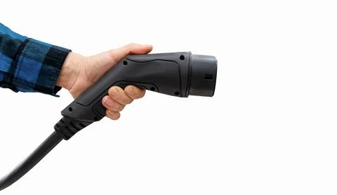 Isolated black EV charging plug in female hand in blue sleeve. Electric car c Stock Photos