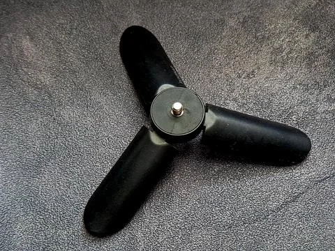 Isolated black mini tripod sits on a textured gray surface, offering stabil.. Stock Photos