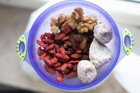 Isolated bright blu plastic cup with dried fruits and nuts. Walnuts, goji, figs Foto stock