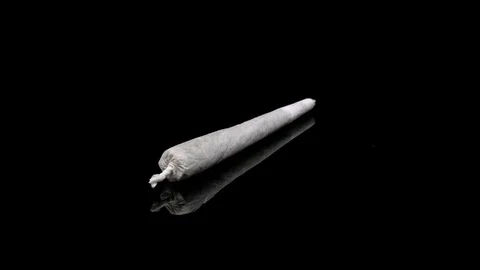 Isolated Cannabis Joint Rotating on a Reflective Surface Looping Stock Footage 108591168