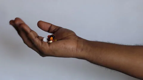 Isolated close shot of a black man's hand opening the fist filled with medicines Stock Footage 147096551