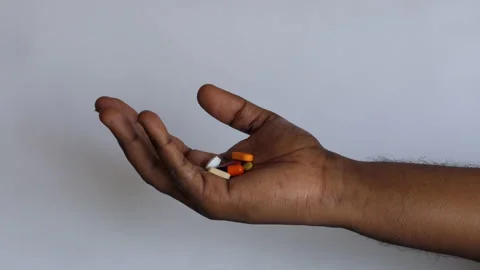 Isolated close shot of a black man's hand with palm filled with a lot of tablets Stock Footage 147096587