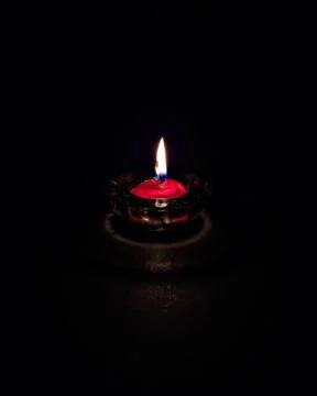 Isolated ,closeup image of small red colored wax lamp(Diya) burning in dark. Stock Photos