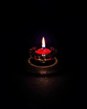 Isolated ,closeup image of small red colored wax lamp(Diya) burning in dark. Stock Photos