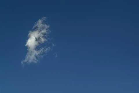 An isolated cloud in the shape of a face on the blue sky Foto stock
