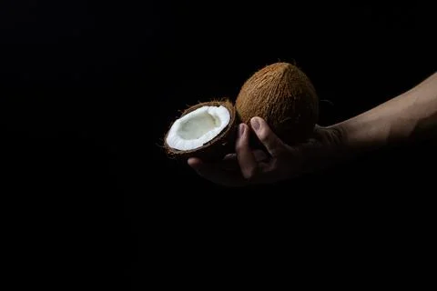 Isolated coconut on a black background. Half and whole coconut in a man's hand o Stock Photos