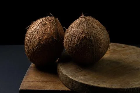 Isolated coconut on a black background. Two whole coconuts on a dark background. Stock Photos