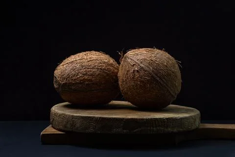 Isolated coconut on a black background. Two whole coconuts on a dark background. Stock Photos