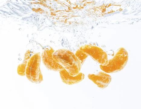 Isolated falling orange segments into water. Peeled pieces of orange fruit in 库存照片