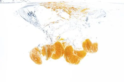 Isolated falling orange segments into water. Peeled pieces of orange fruit in 库存照片