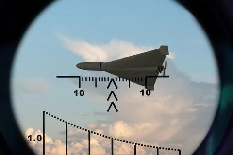 Isolated fixed wing drone aligned in optical sight against cloudy sky Stock Photos