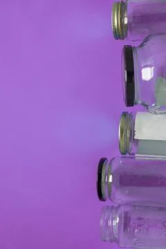Isolated glass jars, flat on violet purple background room, copy space on lef Stock Photos