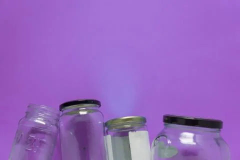 Isolated glass jars, flat on violet purple background, room for copy space to Stock Photos
