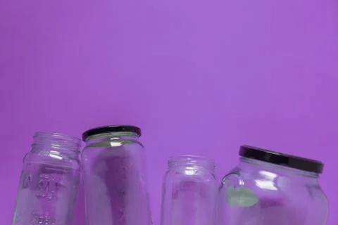 Isolated glass jars, flat on violet purple background, room for copy space to Stock Photos