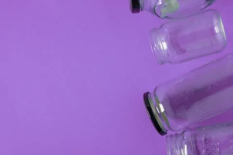 Isolated glass jars, flat on violet purple background room, copy space on lef Stock Photos